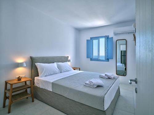 ein weißes Schlafzimmer mit einem Bett und einem Spiegel in der Unterkunft Etherio Apartment III in Piso Livadi