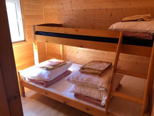 two bunk beds in a wooden room with a window at Domki Letniskowe Kopań in Darłówko