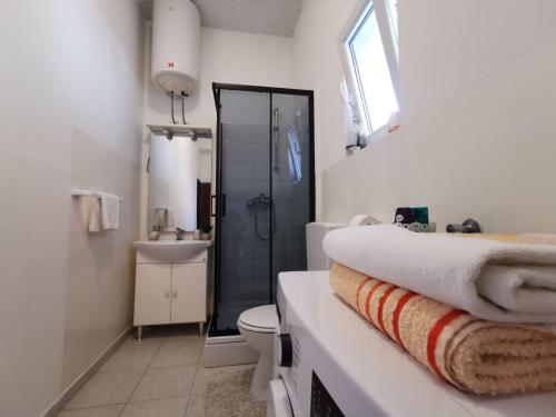 a white bathroom with a toilet and a sink at Priska Apartment in Kaštela