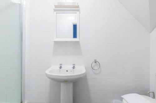 a white bathroom with a sink and a mirror at Brooklands Lodge in Bournemouth