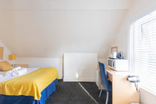 a room with a bed and a desk and a microwave at Brooklands Lodge in Bournemouth