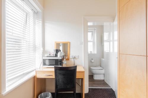 a kitchen with a desk with a microwave and a toilet at Brooklands Lodge in Bournemouth