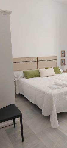 a bedroom with two white beds and a chair at el 2 de Flamenco 2ºA in Cádiz