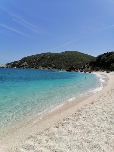 a beach with blue water and a mountain in the background at Large Stone Villa with garden. in Khánia