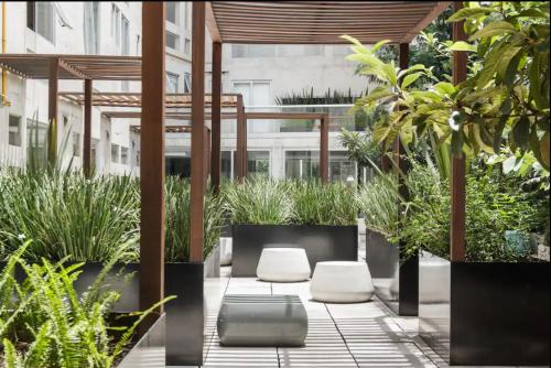 a courtyard with two white chairs and plants at Departamento en Condesa con vista al Castillo de Chapultepec GYM - POOL - PARKING in Mexico City
