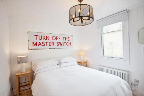 a bedroom with a bed and a sign that reads turn off the master switch at Tin Cabin in peaceful Angus glen in Glenogil