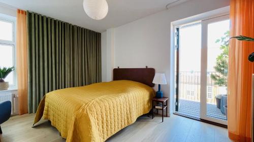 um quarto com uma cama amarela e uma grande janela em ApartmentInCopenhagen Apartment 1499 em Copenhague