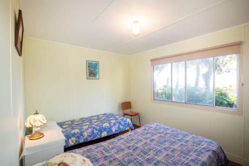 een slaapkamer met twee bedden en een raam bij ARCADIA -Straddie original 3 bedroom house with ocean views in Point Lookout