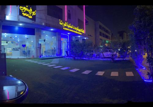 a city street at night with a neon sign at القبة الذهبية1 in Riyadh