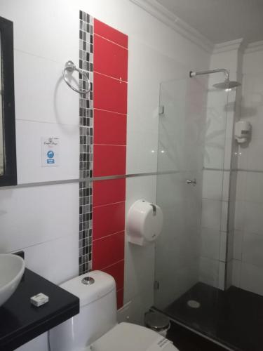a bathroom with a toilet and a glass shower at Confort Plaza Hotel in Villavicencio