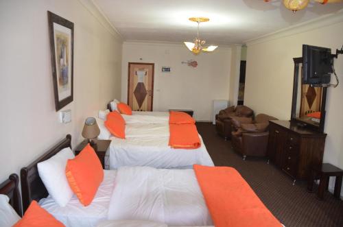 Habitación de hotel con 2 camas con almohadas de color naranja en Casablanca Hotel Ramallah, en Ramallah