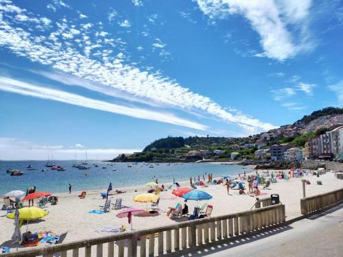 eine Gruppe von Menschen am Strand mit Sonnenschirmen in der Unterkunft Hotel Gran Proa Playa Raxó in Raxo