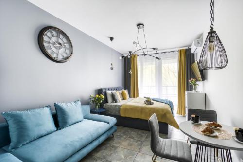 ein Wohnzimmer mit einem blauen Sofa und einem Bett in der Unterkunft Stylowe king studio, metro Słodowiec, parking, park in Warschau