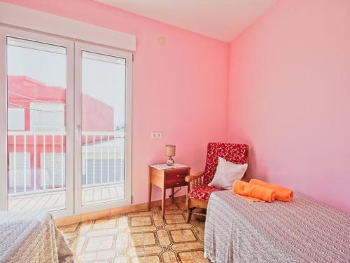 1 dormitorio con paredes rosas, silla y ventana en CASA EN LA PLAYA VALENCIA EL PERELLO en Mareny Barraquetas