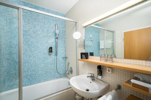 un bagno con vasca, lavandino e doccia di Arthotel ANA Neotel a Stoccarda