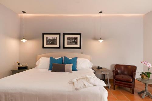 a bedroom with a bed with blue pillows and a chair at Alta Las Palomas Hotel in San José