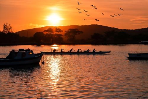 a group of people in a boat on a lake at sunset at Paradiso Corporate in Cabo Frio