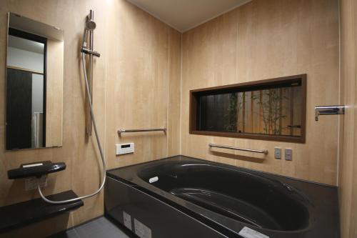 a bathroom with a black tub and a mirror at 農家民宿 山いちご in Echizen