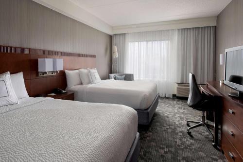 a hotel room with two beds and a desk at Sonesta Select Boston Milford in Milford