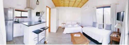 a living room with a white kitchen with a white couch at Los Bungalows in José Ignacio