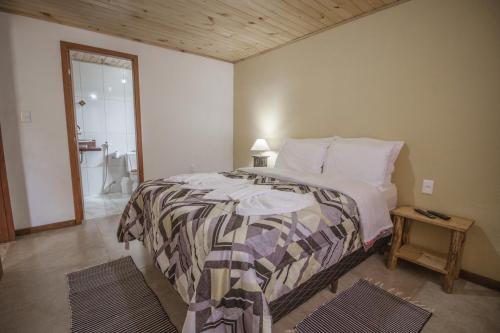 a bedroom with a large bed and a bathroom at Chalés Cerejeira in Visconde De Maua