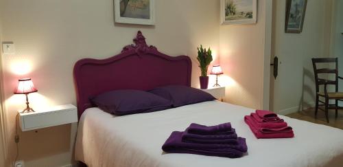La maison de Louise في فونتيناي لو كومت: غرفة نوم مع سرير وفوط أرجوانية عليه