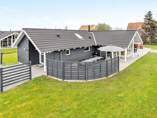 ein schwarzes Haus mit einem Zaun und einem Hof in der Unterkunft 14 person holiday home in Sydals in Høruphav