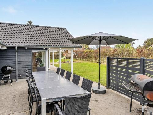 un patio con mesa y sombrilla en 14 person holiday home in Sydals, en Høruphav