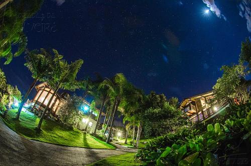 a night view of a resort with palm trees at Pousada Moradas da Silveira in Garopaba