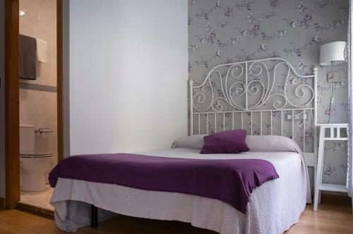 a bedroom with a white bed with a purple blanket at Balenax Pensión in Gijón