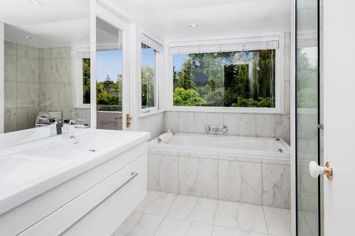 baño blanco con bañera y ventana en French City Mansion - Christchurch Luxury Home en Christchurch