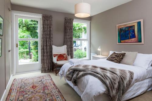 a bedroom with a large bed and two windows at French City Mansion - Christchurch Luxury Home in Christchurch