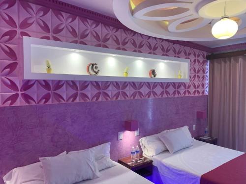 a purple room with two beds and a purple wall at Hotel Boutique TEKALI INN in Cuetzalán del Progreso