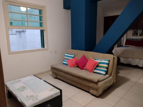 a living room with a couch with colorful pillows at Apartamento no coração de Poços de Caldas in Poços de Caldas