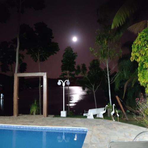 a pool at night with the moon in the background at Nosso Recanto Pérola in Capitólio