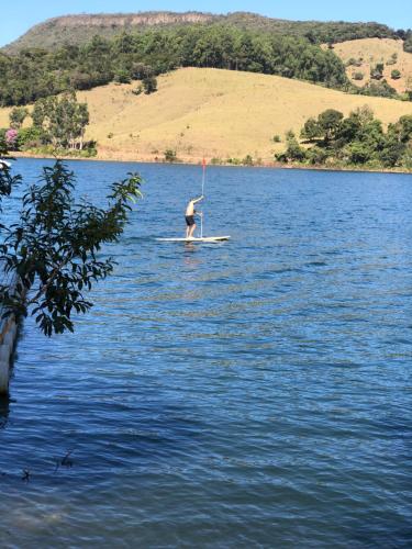 a man standing on a paddle board on a lake at Nosso Recanto Pérola in Capitólio
