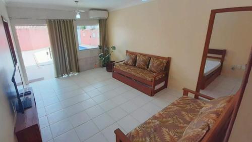 a room with a bed and a couch and a window at Para 20 Pessoas com Piscina e Churrasqueira. in Porto Seguro
