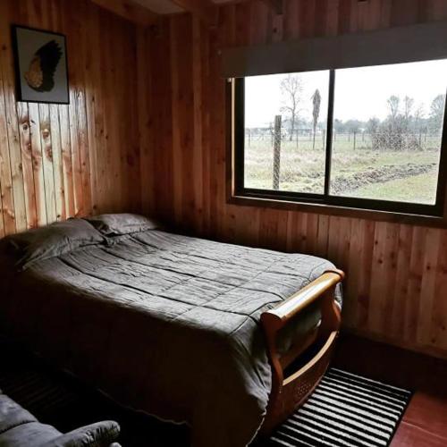 PichilにあるCabaña Relmu Osorno con tinajaの窓のある部屋にベッドがある寝室