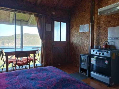 ein Schlafzimmer mit einem Bett, einem Tisch und einem Herd in der Unterkunft Cabaña pumillahue rural in Ancud