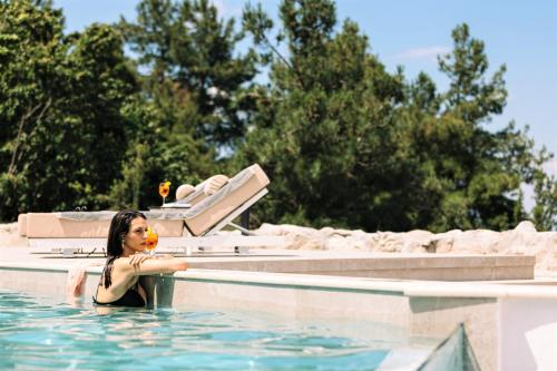 a woman in a swimming pool with a flower in her mouth at Akrotiri Olympus Luxury Suites - Adults Only in Plaka Litochorou