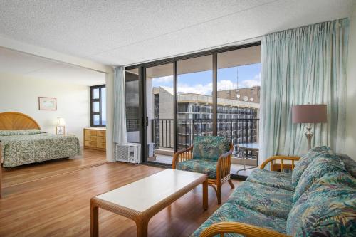 a living room with a couch and a bed at Aston at the Waikiki Banyan in Honolulu