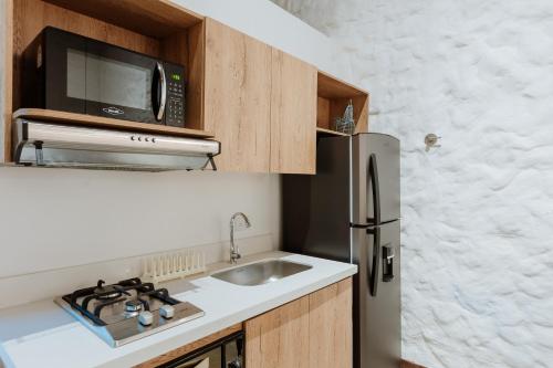 a kitchen with a sink and a microwave and a refrigerator at La Casa de Nelly - Medellín in Medellín