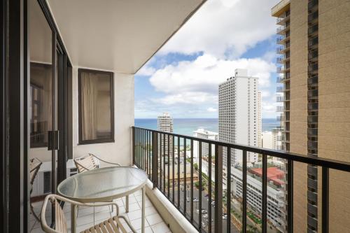 a balcony with a chair and a view of the ocean at Aston at the Waikiki Banyan in Honolulu