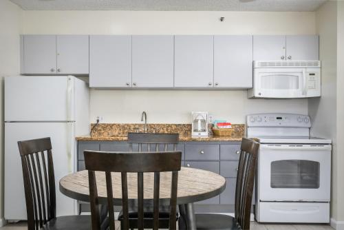 a kitchen with white cabinets and a table with chairs at Aston at the Waikiki Banyan in Honolulu