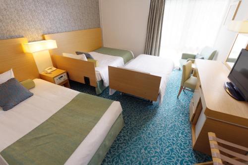 a hotel room with two beds and a television at Art Hotel Narita in Narita