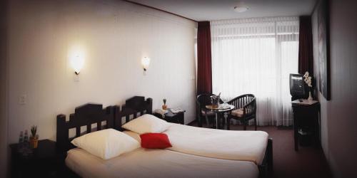 デン・ヘルダーにあるHotel Den Helderのベッドルーム1室(白いシーツと赤い枕のベッド1台付)