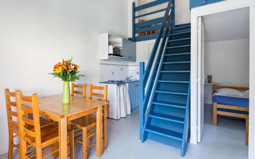 une salle à manger avec une table et un escalier bleu dans l'établissement Lagrange Vacances Le Clos des Chênes, aux Mathes