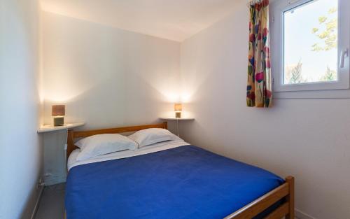 a bedroom with a blue bed and a window at Lagrange Vacances Le Clos des Chênes in Les Mathes