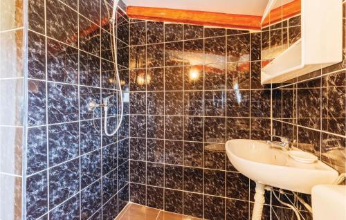 a bathroom with a sink and a black tiled wall at Nice Apartment In Vodnjan With 2 Bedrooms And Wifi in Vodnjan