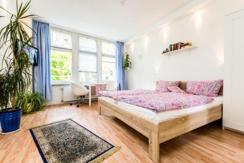 a bedroom with a bed and a desk and windows at CGN Apartments - Altstadt in Cologne